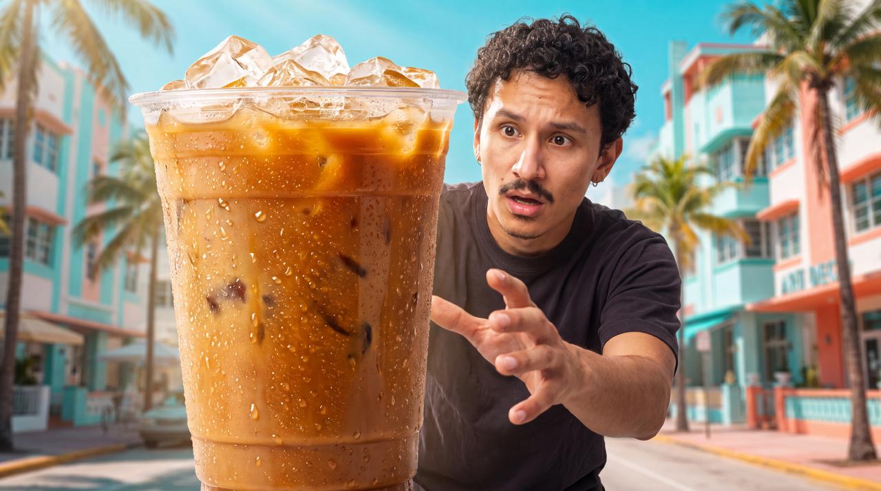 Hombre sorprendido extendiendo la mano hacia un café helado gigante en una colorida calle de Miami